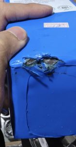 A li-ion battery has cracks on the outer casing due to it was punctured by a metal piece