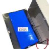 A battery with a blue heatshrink lies in a white electrical box, with wiring of black and white, and some small communication cords.
